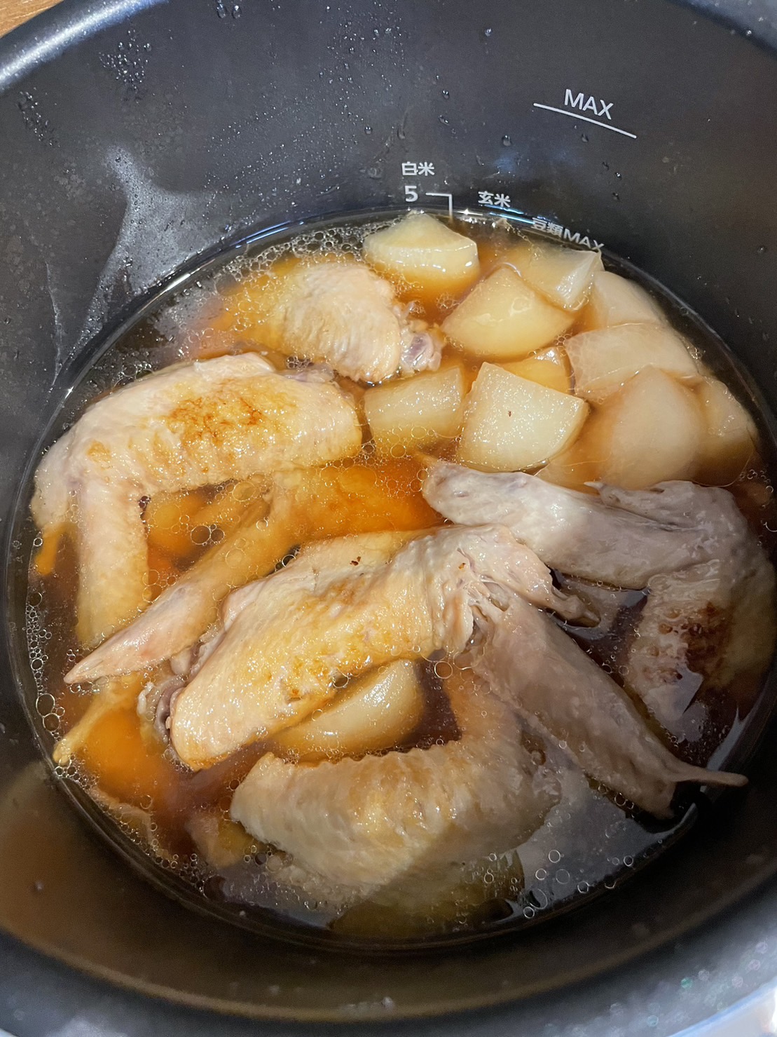 圧力鍋の中の鶏手羽肉と大根の煮込み